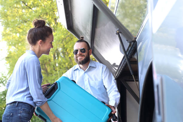 The passenger inserts the suitcase into the luggage compartment on the bus. The driver helps the passenger put the suitcase in the trunk. coach bus photos stock pictures, royalty-free photos & images