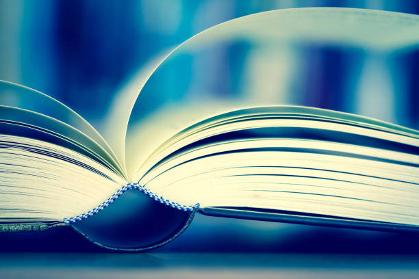istock Close up opened book page with blurry bookshelf background for education and publication concept , extremely DOF with vintage retro color tone 831954182