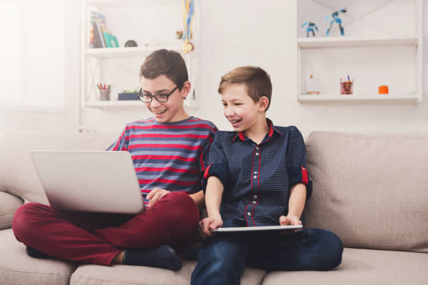 istock Two teenage boys with gadgets on couch at home 831962796