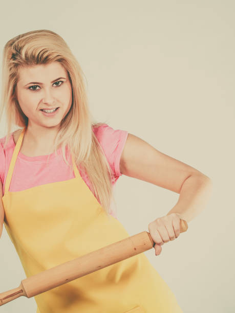 istock Woman wearing apron holding rolling pin 831968544