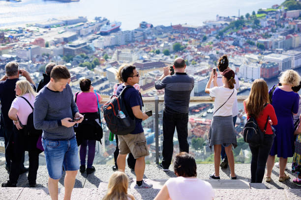 Crowd enjoying the view from top of Mount Fløyen. Bergen city Bergen, Norway - August 9, 2017: Crowd enjoying the view from top of Mount Fløyen. Bergen city including Fisketorget and Bryggen seen in background. Cruising ships in port. fløyen stock pictures, royalty-free photos & images