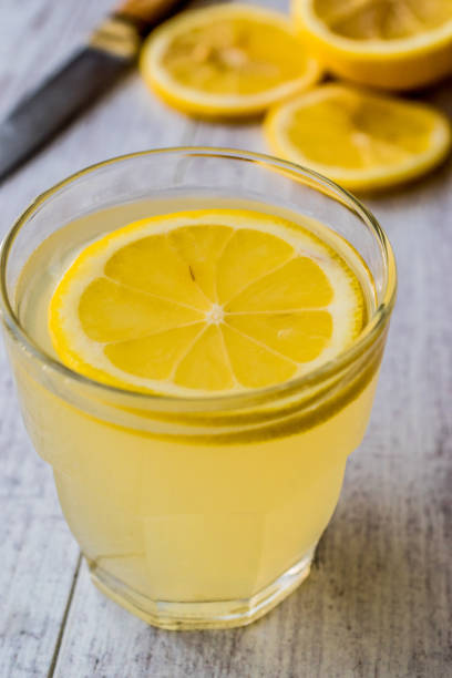 istock Lemon Liqueur Limoncello with lemon on white wooden surface. 831986134