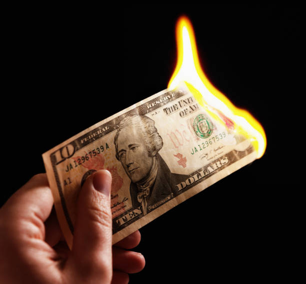 istock Hand holds burning American Ten Dollar bill 831987258
