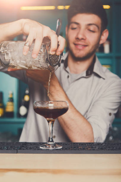 istock Young bartender pouring cocktail drink into glass 832002954