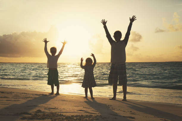 istock father with son and daughter silhouettes play at sunset beach 832027106