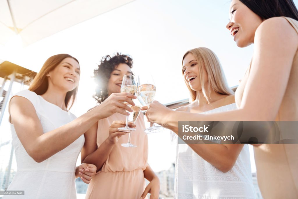 Joyful happy women having a celebration Hen party. Joyful happy young women standing together and cheering with champagne while having a celebration Party - Social Event Stock Photo