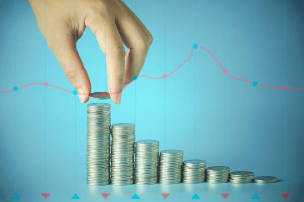 istock hand stacked money coins with graph on blue background 832056714