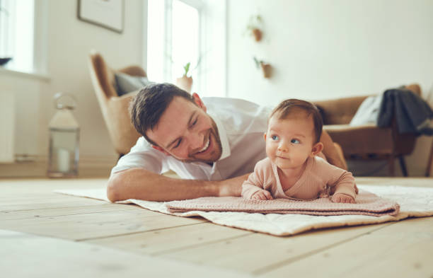 улыбающийся отец лежит дома со своей младенческой дочерью - baby blanket стоковые фото и изображения