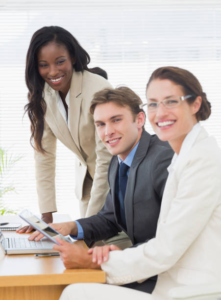 istock Smiling colleagues with laptop and digital tablet in meeting 832074530