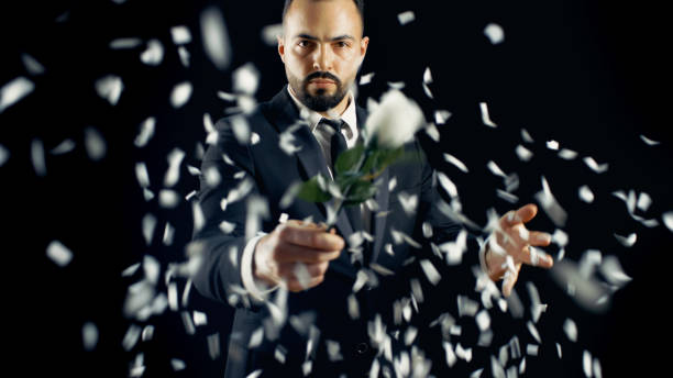 Professional Magician Performs Flower (Rose) Bud Disappearing and Appearing Spectacular Trick. The Background is Black.