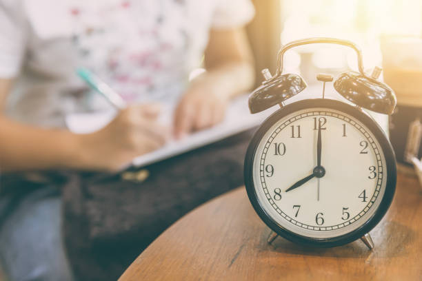 istock time for working concept. clock timed at 8 o'clock with blur working people background. 832086138