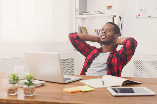 istock Relaxed black businessman with laptop in modern white office 832088782