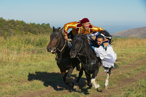 Circa Almaty, Kazakhstan - September 18, 2011: Unidentified people wearing national dresses ride on horseback at countryside, Almaty, Kazakhstan.