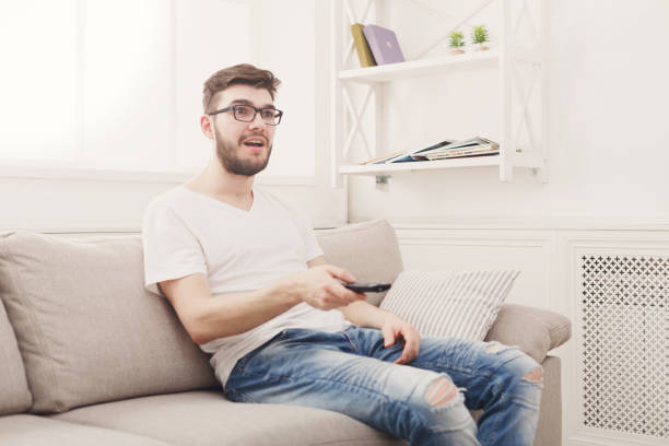 istock Amused young man wathing tv at home 832100932