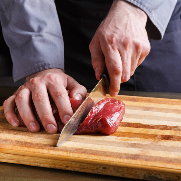 istock Chef cutting filet mignon on wooden board at restaurant kitchen 832102230