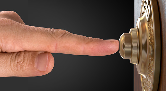 A male finger pressing a vintage brass doorbell on an isolated wooden background - 3D render