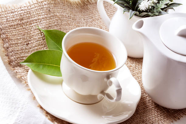 nahaufnahme bio-tee in weißer tasse mit grünem blatt, tee-zeremonie zeitkonzept - jasmine tea black tea tea drink stock-fotos und bilder
