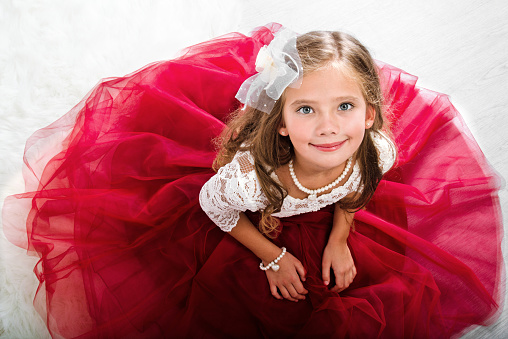 Adorable smiling little girl child in princess dress sitting on the floor