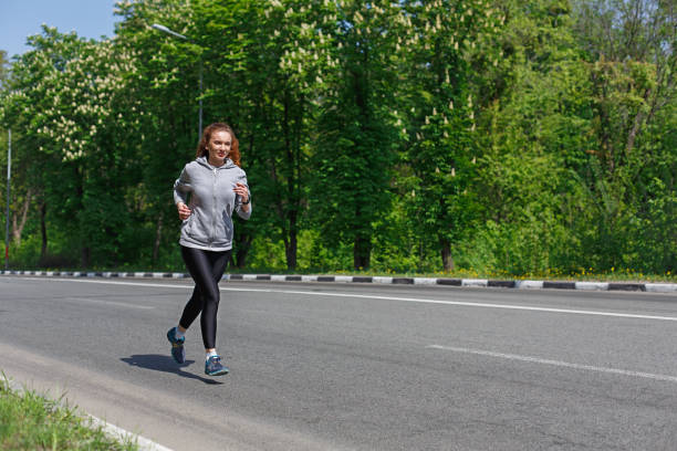 istock Young woman running on road, copy space 832120080