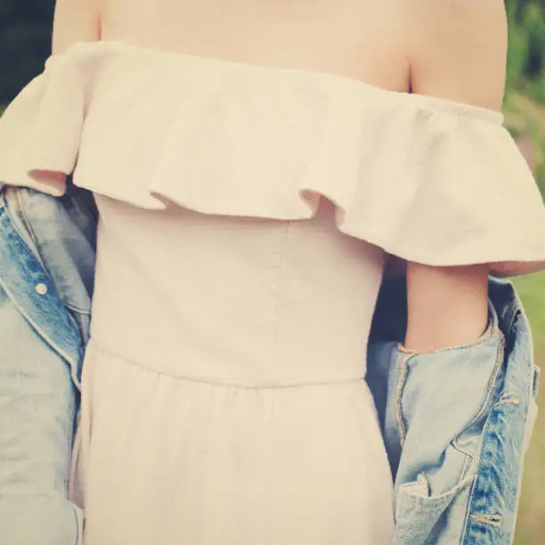 Girl dressed pale pink dress and denim jacket walking in park. Landscape background.