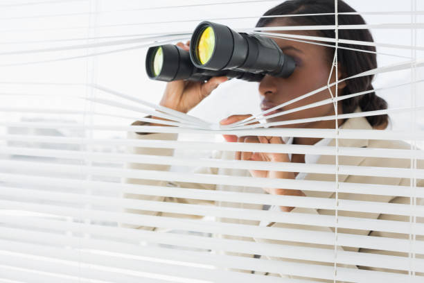istock Businesswoman peeking with binoculars through blinds 832124954