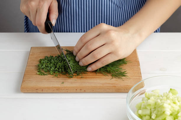istock Step by step recipe for tarator. Hands cut a dill on board in the kitchen. 832125474
