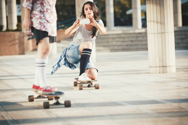 istock Girlfriends skateboarding and photographing with mobile phone 832133730