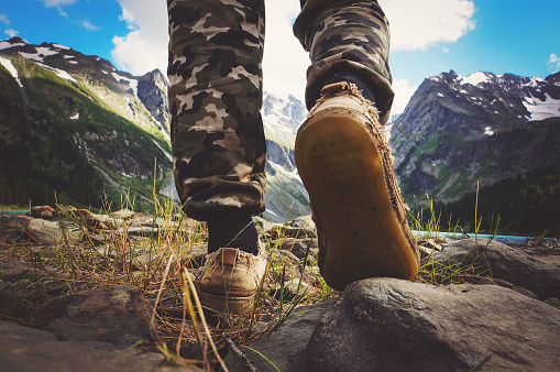 hikers go along mountain ridge. Feet boots hiking Traveler alone outdoor wild nature Lifestyle Travel extreme survival concept summer adventure vacations steps sole view from below