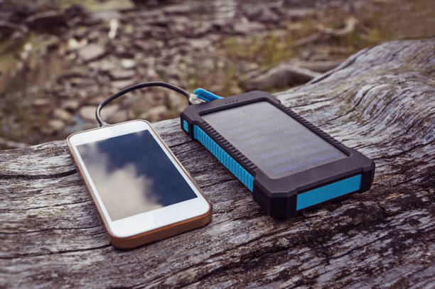 solar power bank charging smart phone solar power bank charging smart phone lying on a log portable power bank stock pictures, royalty-free photos & images