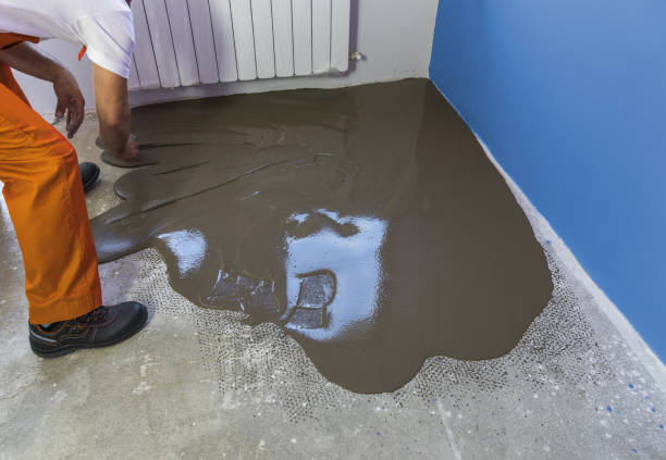 istock Worker puts a self leveling screed with tool on concrete floor in house 832146674