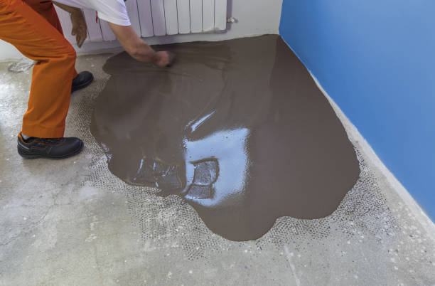 istock Worker puts a self leveling screed with trowel on concrete floor in house 832147058