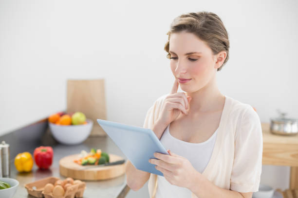 istock Concentrating young woman using her tablet standing in her kitchen 832150710