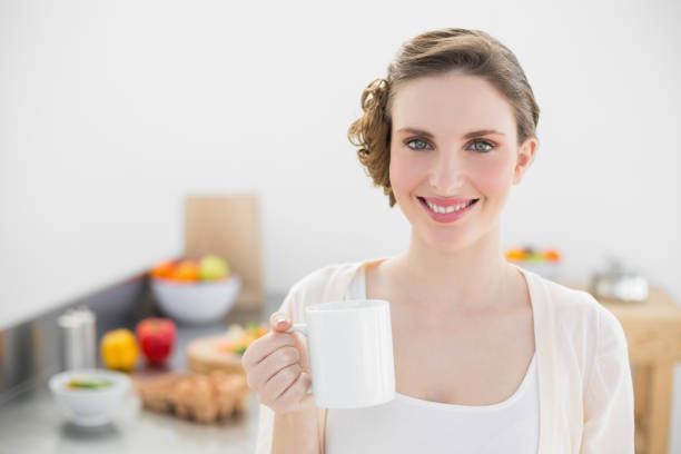 istock Cheerful lovely woman standing in her kitchen holding a cup 832150794