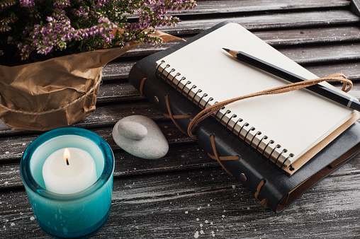 Notebook, heather flowers, candles, on old wooden background