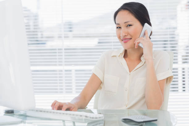 istock Businesswoman using cellphone and computer at desk 832167084