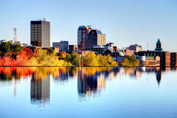 Manchester New Hampshire skyline along the banks of the Merrimack River in autumn. Manchester is the largest city in the state of New Hampshire and the largest city in northern New England. Manchester is known for its industrial heritage, riverside mills, affordability, and arts & cultural destination.