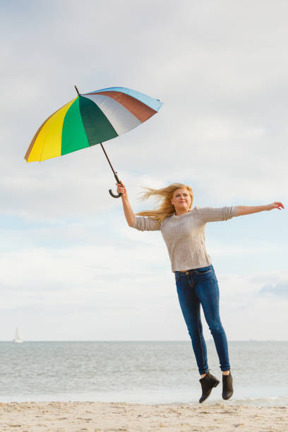 istock Woman jumping with colorful umbrella on beach 832170616