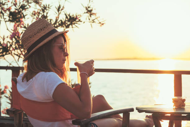istock Young woman enjoying sunset at a beach bar 832174618