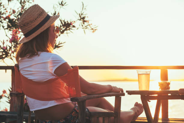 istock Young woman enjoying sunset at a beach bar 832174622