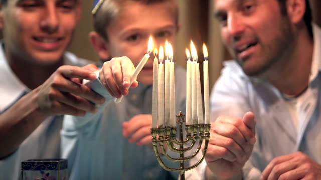 Father and sons lighting menorah