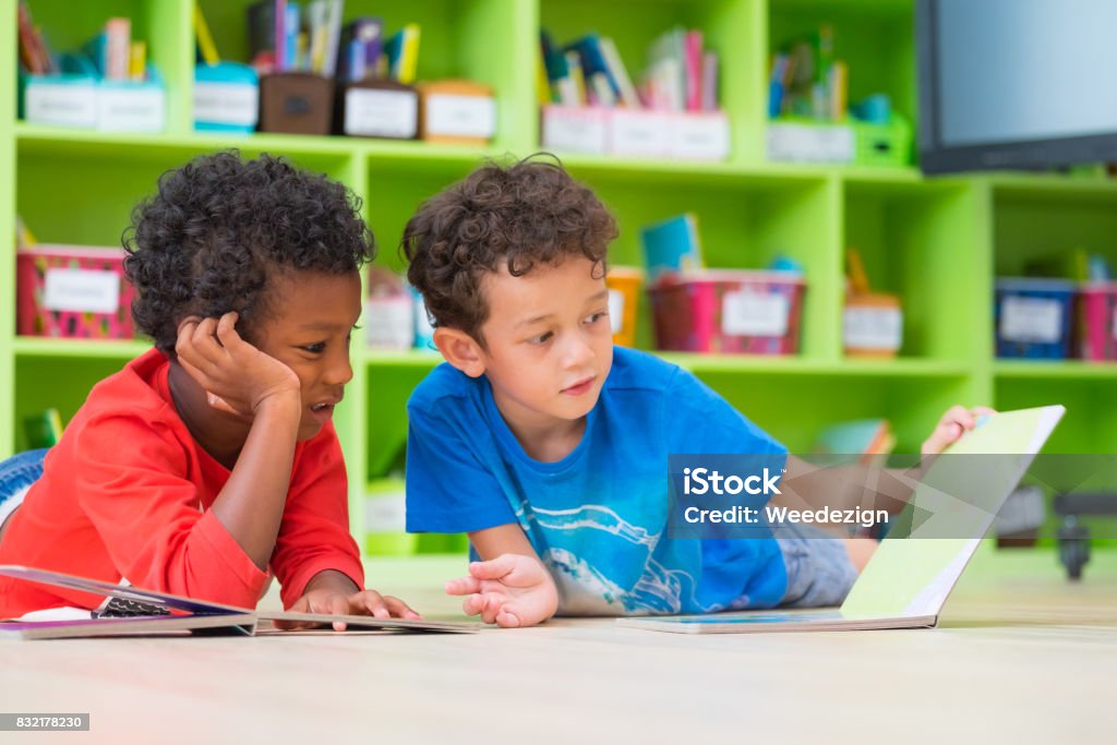 Zwei junge Kind legte sich auf den Boden und lesen Märchen Buch im Vorschulalter Bibliothek, Kindergarten Schule Bildungskonzept - Lizenzfrei Kind Stock-Foto