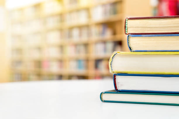 Stack and pile of books on table in public or school library.