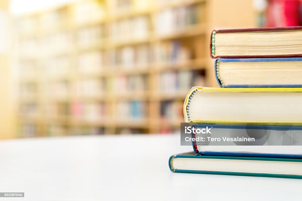 Stack and pile of books on table in public or school library. Education, studying and literature service concept with negative copy space. Stack and pile of books on table in public or school library. Book Stock Photo