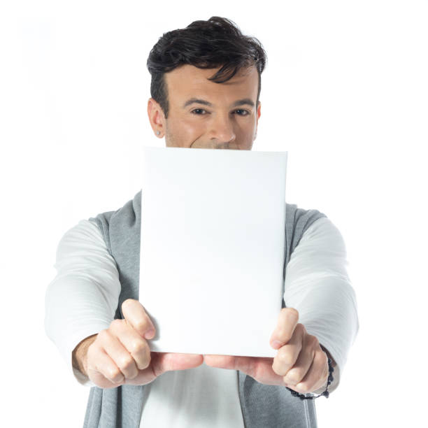 istock Charming man holds a blank and rectangular paper. Handsome brazilian wearing gray and white clothes, neutral. 832237914
