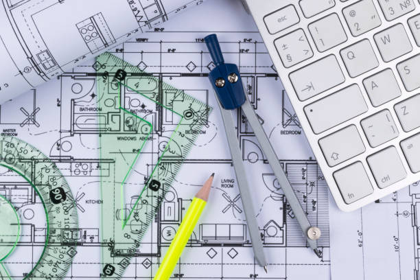 istock Architectural blueprints drawings of the modern house with computer keyboard. Architectural blueprints and blueprint rolls and a drawing instruments on the worktable. Drawing compass, plans. 832242732