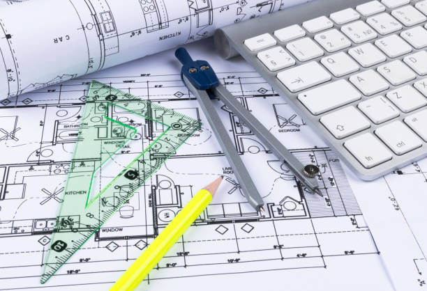 istock Architectural blueprints drawings of the modern house with computer keyboard. Architectural blueprints and blueprint rolls and a drawing instruments on the worktable. Drawing compass, plans. 832243372