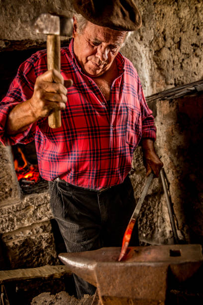 istock Senior Blacksmith Man Forging Iron Craft on Anvil 832254410