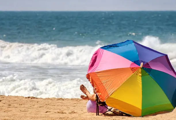 Beach scene with colorful beach umbrella on the sand and breaking waves.