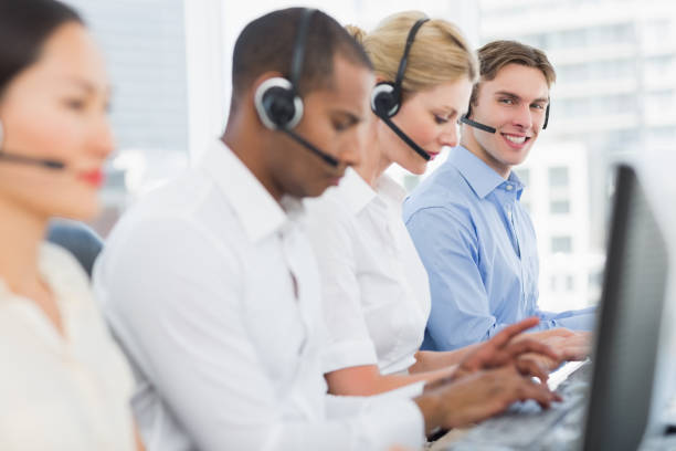istock Business colleagues with headsets using computers at desk 832260996