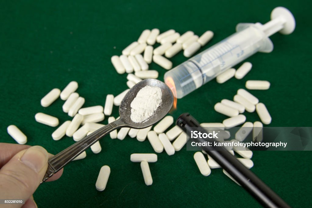 Opiods with money and syringe Crushed powdered opioids in spoon with money, pills and syringe. Fentanyl Stock Photo